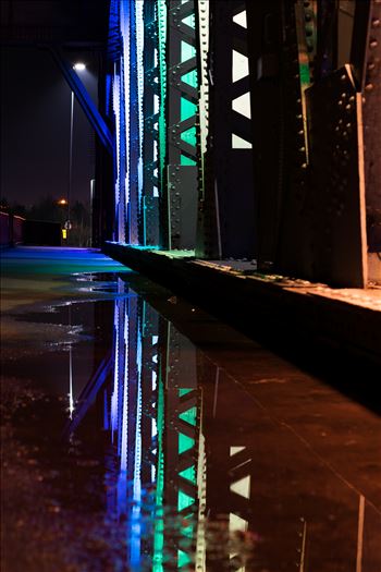 A photo of the lights on Newport Bridge and a puddle reflection.